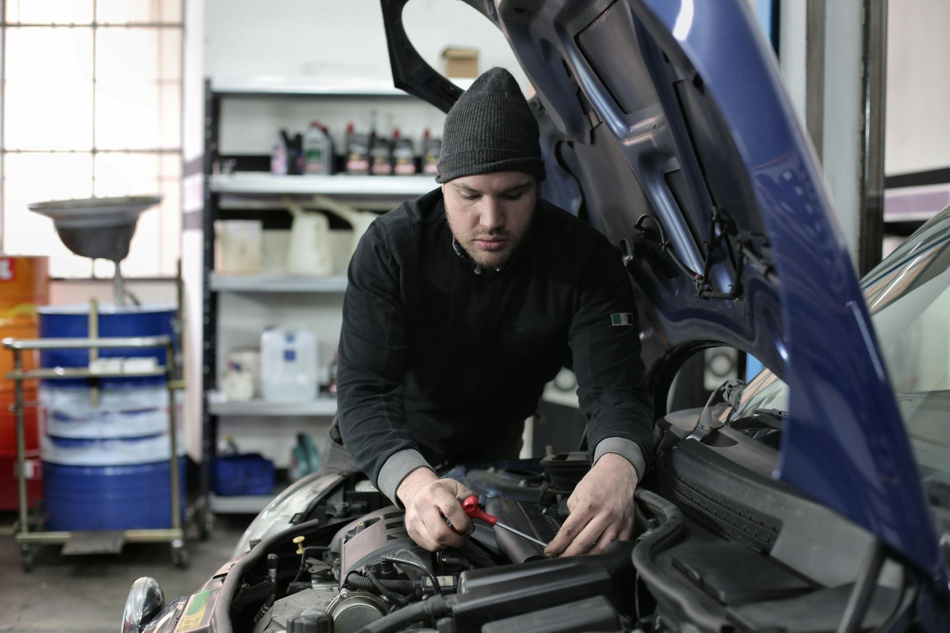 A mechanic working on a car engine in a garage.