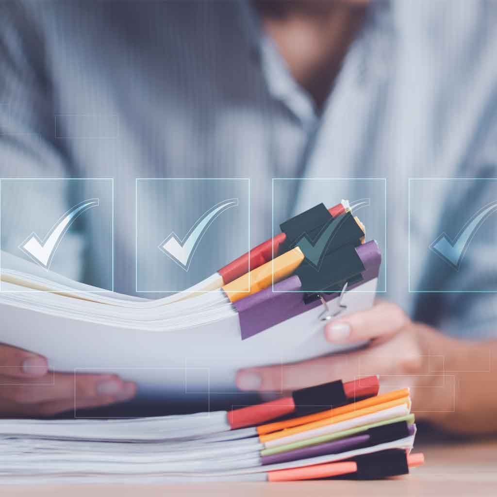 A person holding a stack of paperwork divided by colourful index tabs.